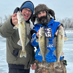 Two anglers holding walleye on a frozen lake.