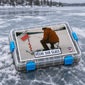 Target Box Pêche sur glace de Target Baits Leurres, coffret fermé à attaches bleues posé sur la surface givrée d’un lac.