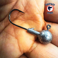 Unpainted round jig head with a black hook, held in a hand.