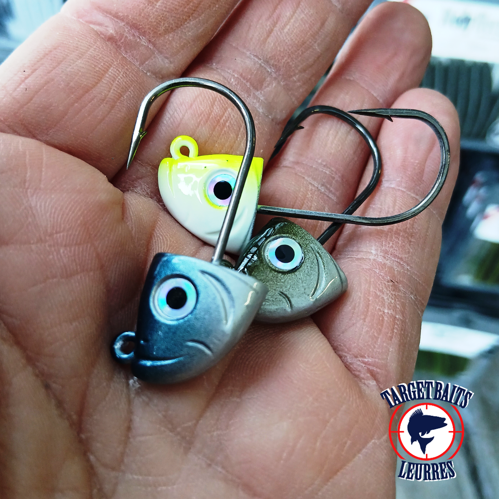 Trois têtes de jig Shad 3D bleue, verte et chartreuse présentées dans une main.