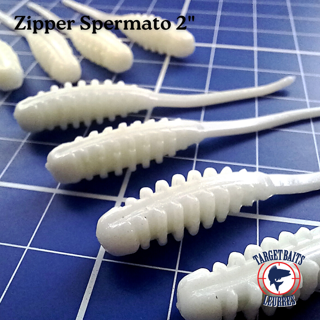 Leurres souples Zipper Spermato blancs de 2 po alignés sur un tapis quadrillé.